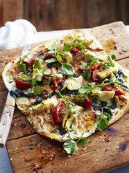 Pancetta, artichoke and chicory pizza on serving board, close-up - CUF11669