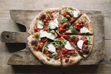 Sliced pizza on chopping board, overhead view - CUF11680