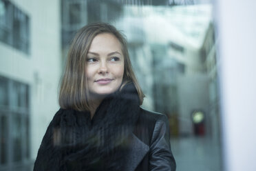 Bürofensterporträt einer jungen Geschäftsfrau mit Blick zur Seite - CUF11762