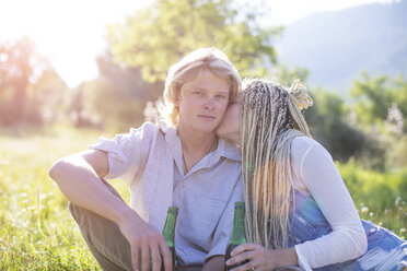 Romantisches junges Paar, das mit einer Flasche Bier auf einem Feld sitzt, Mallorca, Spanien - CUF11820