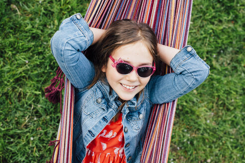 Portrait of smiling girl wearing sunglasses lying in hammock - ANHF00046