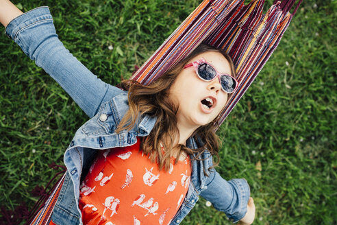 Portrait of singing girl wearing sunglasses lying in hammock - ANHF00047