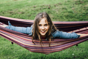 Portrait of smiling girl lying in hammock sticking out tongue - ANHF00049