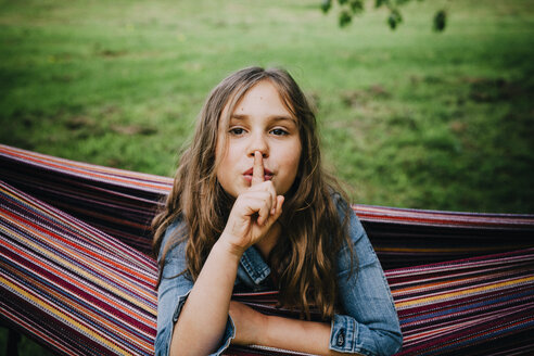 Porträt eines Mädchens in der Hängematte mit Finger auf dem Mund - ANHF00050