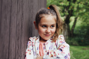 Portrait of smiling girl leaning against wooden wall - ANHF00056