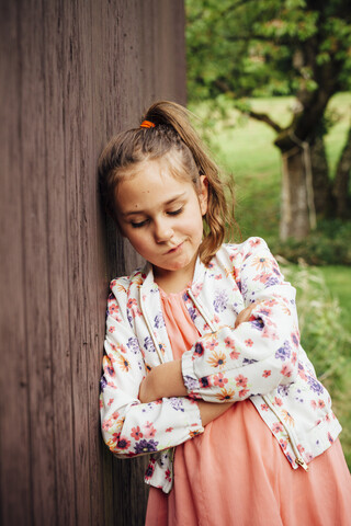 Porträt eines traurigen Mädchens, das an einer Holzwand lehnt, lizenzfreies Stockfoto