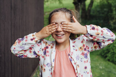 Porträt eines lächelnden Mädchens, das seine Augen mit den Händen bedeckt - ANHF00059