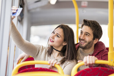 Großbritannien, London, Porträt eines lächelnden jungen Paares, das im Bus ein Selfie mit seinem Smartphone macht - WPEF00268