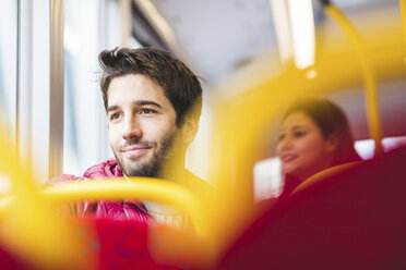 Großbritannien, London, Porträt eines lächelnden jungen Mannes im Bus, der aus dem Fenster schaut - WPEF00273