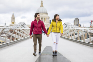 UK, London, young couple walking hand in hand on bridge in front of St Pauls Cathedral - WPEF00277