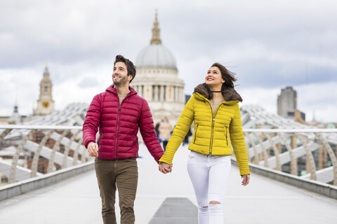 UK, London, junges Paar geht Hand in Hand auf der Brücke vor der St. Pauls Cathedral, lizenzfreies Stockfoto
