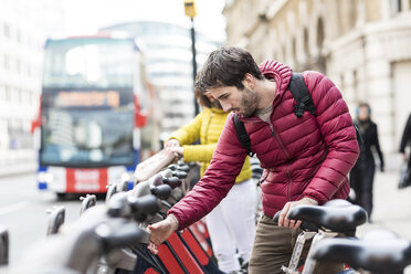 UK, London, junger Mann leiht sich ein Fahrrad am Fahrradständer in der Stadt - WPEF00291