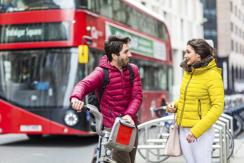 UK, London, junger Mann mit Leihfahrrad vom Fahrradverleih im Gespräch mit seiner Freundin, lizenzfreies Stockfoto