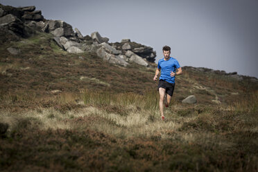 Männlicher Läufer beim Abstieg von Stanage Edge, Peak District, Derbyshire, UK - CUF11862