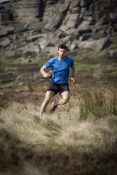 Männlicher Läufer beim Abstieg von Stanage Edge, Peak District, Derbyshire, UK - CUF11863