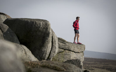 Männlicher Läufer mit Blick vom Gipfel des Stanage Edge, Peak District, Derbyshire, UK - CUF11866