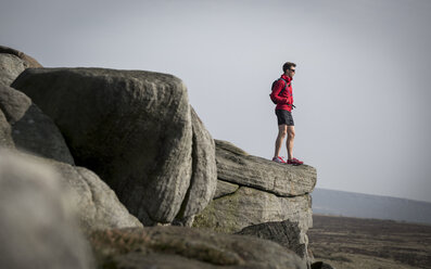 Male runner looking out from top of Stanage Edge, Peak District, Derbyshire, UK - CUF11866