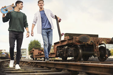 Zwei junge Männer gehen mit Skateboards entlang der Bahngleise, Bristol, UK - CUF11885