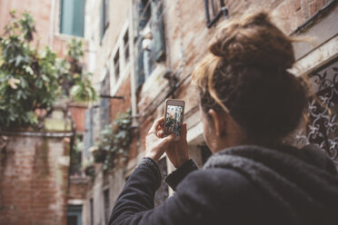 Blick über die Schulter einer Frau, die mit ihrem Smartphone Gebäude fotografiert, Venedig, Italien - CUF11926
