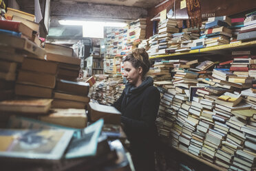 Junge Frau beim Stöbern in einem gestapelten Buchladen, Venedig, Italien - CUF11931