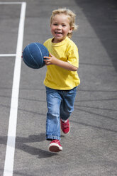 Preschool boy running with ball in preschool yard - CUF11979