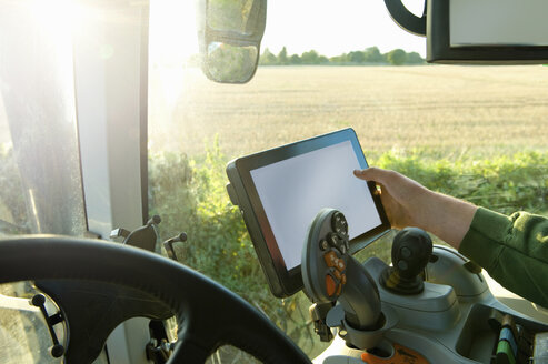 Die Hand eines Landwirts, der seinen Traktor über einen Touchscreen mit einem globalen Positionierungssystem steuert - CUF11995