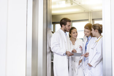 Männliche und weibliche Ärzte benutzen ein digitales Pad und sprechen im Krankenhaus - CUF11998