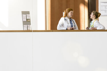 Zwei junge Ärztinnen lehnen an einem Krankenhausbalkon und unterhalten sich - CUF12004