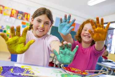 Portrait of primary schoolgirls with painted hands in classroom - CUF12016