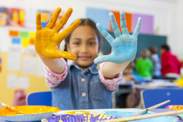 Portrait of primary schoolgirl with painted hands in classroom - CUF12017