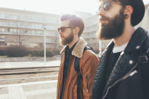 Seitenansicht von zwei jungen männlichen Hipster-Freunden mit Sonnenbrillen in einer städtischen Wohnsiedlung - CUF12027