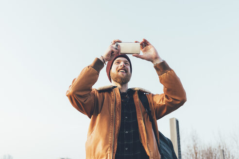 Glückliche junge männliche Hipster nehmen Smartphone Selfie gegen blauen Himmel - CUF12041