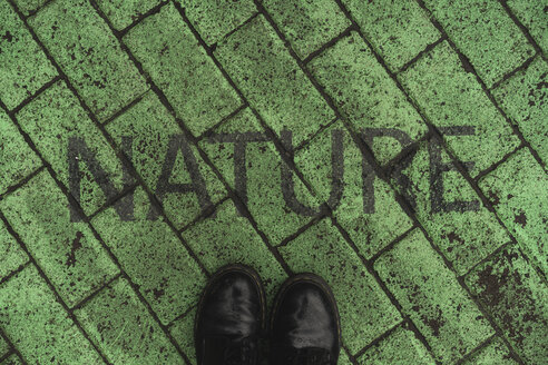 Black shoes on green pavement with stenciled word 'Nature' - AFVF00494