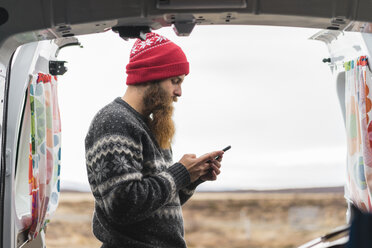 Hipster steht am Lieferwagen und benutzt ein Mobiltelefon - AFVF00509