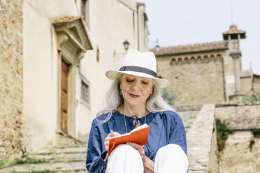 Stilvolle reife Frau schreibt in ein Notizbuch vor einer Kirche, Fiesole, Toskana, Italien - CUF12080