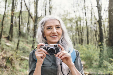 Ältere Frau mit langen grauen Haaren beim Fotografieren im Wald, Scandicci, Toskana, Italien - CUF12084