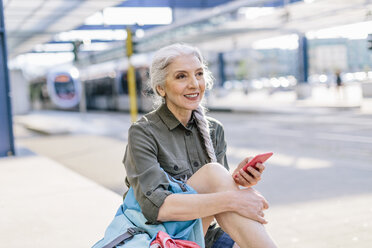 Ältere Rucksacktouristin mit Smartphone am Busbahnhof, Scandicci, Toskana, Italien - CUF12089