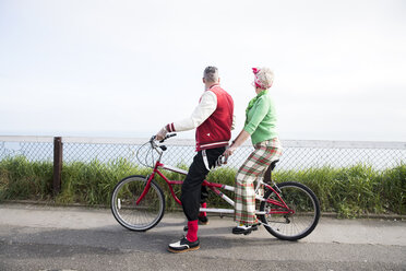 1950's vintage style couple looking out from tandem bicycle at coast - CUF12107