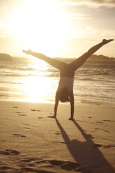 Young woman doing handstand on beach, Schotsche kloof, Western Cape, South Africa, Africa - CUF12149