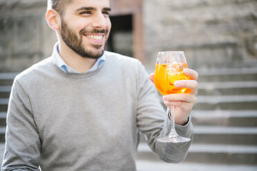 Portrait of young man, outdoors, raising glass - CUF12154