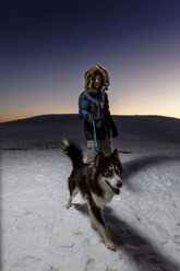 Älterer Mann, der nachts mit seinem Hund im Schnee spazieren geht - CUF12213