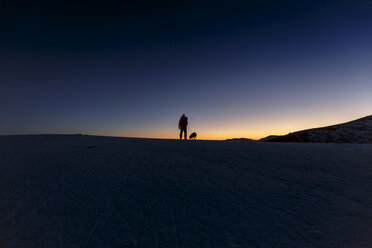 Silhouettierte Ansicht eines Mannes und eines Hundes auf einem Hügel am nächtlichen Horizont - CUF12214