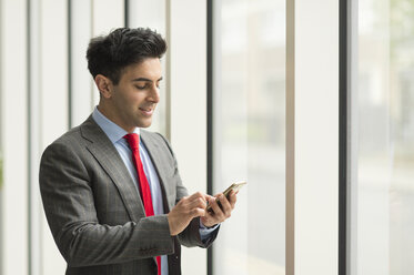 Geschäftsmann mit Smartphone-Touchscreen am Bürofenster - CUF12314