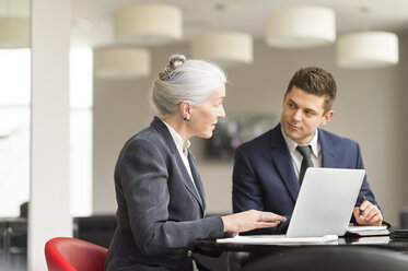 Businesswoman explaining to male colleague in boardroom meeting - CUF12349