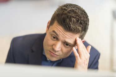 Besorgter Geschäftsmann schaut im Büro auf den Computer - CUF12351