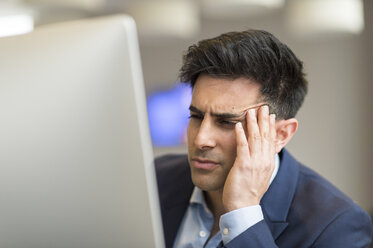 Confused businessman looking at computer in office - CUF12352