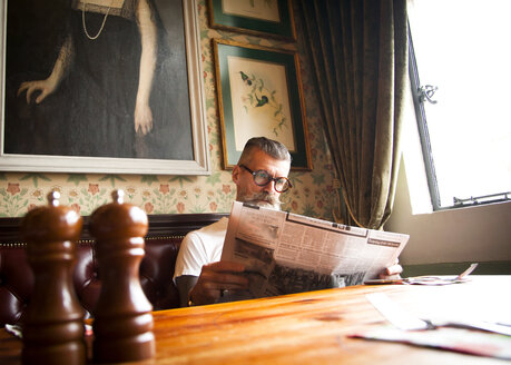 Schrulliger Mann, der in einer Bar und einem Restaurant Zeitung liest, Bournemouth, England - CUF12378
