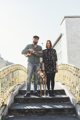 Porträt eines coolen Paares mit Hund, das auf einem Steg steht - CUF12409
