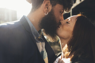 Cool couple kissing on sunlit street - CUF12415