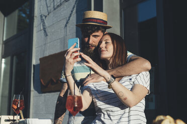 Couple taking smartphone selfie at sidewalk cafe - CUF12418